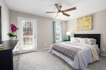 Bedroom with a patio access door, a window, and a ceiling fan.